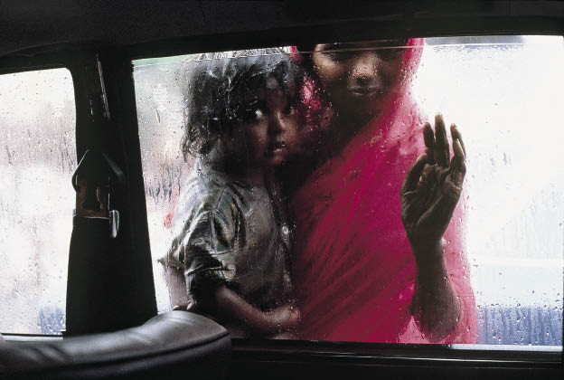  ИНДИЯ. Бомбей. 1993. Мать и ребенок просят милостыню через окно такси во время муссона